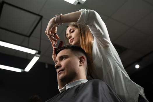 Haircut and styling in barbershop for handsome man. Woman making hairstyle using scissors