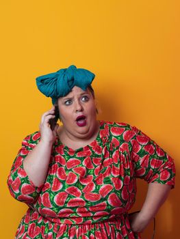 Trendy plus size woman having conversation talking by smartphone over yellow background smiling with an idea or question pointing finger with happy face, number one. High quality photo