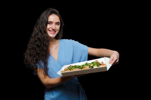 Woman courier with pinsa romana gourmet italian cuisine on black background. Holding scrocchiarella traditional dish. Food delivery from pizzeria. Pinsa with meat, arugula, olives, cheese