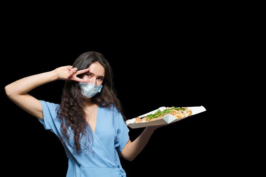 Girl courier with scrocchiarella gourmet italian cuisine on black background. Holding pinsa romana traditional dish. Food delivery from pizzeria. Pinsa with meat, arugula, olives, cheese.