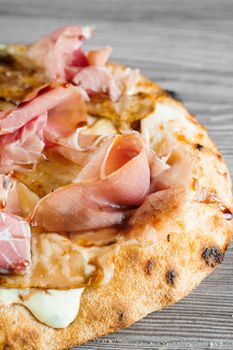 Scrocchiarella with pear, cheese, prosciutto on grey wooden background. Pinsa romana gourmet italian cuisine. Junk food.