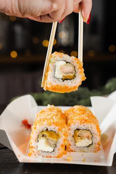 Sushi and roll food delivery at new year eve. Christmas celebration with roll with salmon, mango and soft cheese