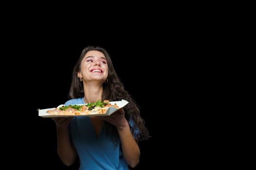 Woman courier with pinsa romana gourmet italian cuisine on black background. Holding scrocchiarella traditional dish. Food delivery from pizzeria. Pinsa with meat, arugula, olives, cheese