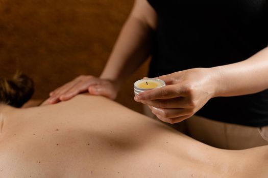 Waxing body massage with candle. Beauty spa procedure. Thai massage with warm wax