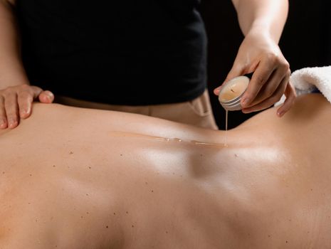 Waxing body massage with candle. Beauty spa procedure. Thai massage with warm wax