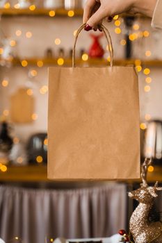 Craft bag for shopping at new year eve. Bag on christmas lights background. New year sale. Vertical photo for social