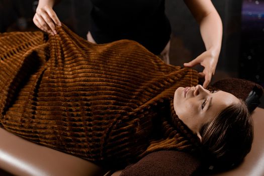 Full body wrap in warm blanket after chocolate massage beauty treatment for female model in spa