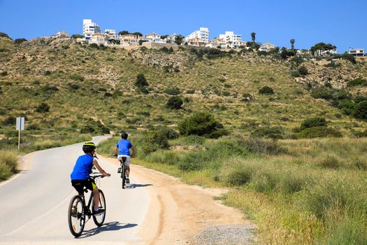 Santa Pola, Alicante, Spain- May 6, 2022: Cyclist riding along the road that borders little beaches of the Lighthouse in Santa Pola, Alicante