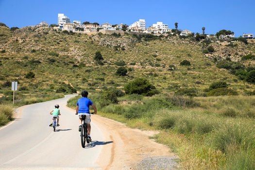 Santa Pola, Alicante, Spain- May 6, 2022: Cyclist riding along the road that borders little beaches of the Lighthouse in Santa Pola, Alicante