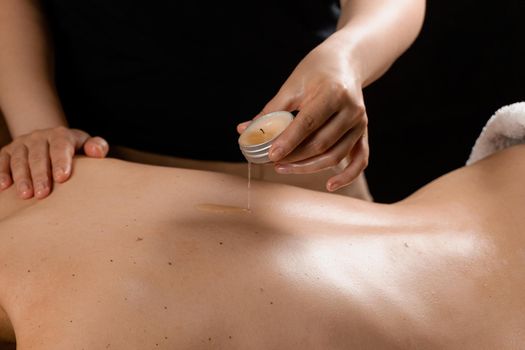 Waxing body massage with candle. Beauty spa procedure. Thai massage with warm wax