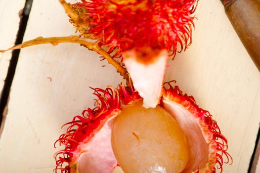 fresh tropical rambutan fruits over rustic wood table 