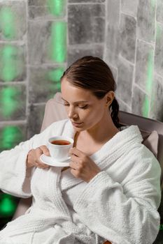 Inhalation therapy in salt room in spa. Young woman with cup of tea relaxing