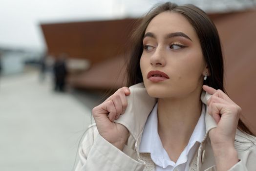 Outdoor portrait of a young beautiful fashionable lady wearing stylish coat . Model looking aside. Female fashion concept. City lifestyle. Close up. big plump lips