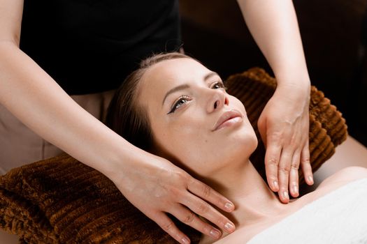 Facial massage close-up in spa center. Girl with perfect skin relaxing in massage room