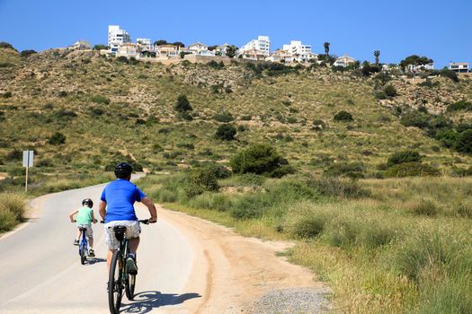 Santa Pola, Alicante, Spain- May 6, 2022: Cyclist riding along the road that borders little beaches of the Lighthouse in Santa Pola, Alicante