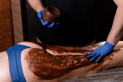 Chocolate massage for legs and hips of young woman. Chocolate wrap spa treatment