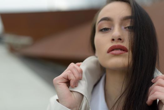 Outdoor portrait of a young beautiful fashionable lady wearing stylish coat . Model looking aside. Female fashion concept. City lifestyle. Close up. big plump lips
