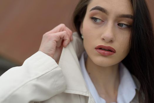 Outdoor portrait of a young beautiful fashionable lady wearing stylish coat . Model looking aside. Female fashion concept. City lifestyle. Close up. big plump lips