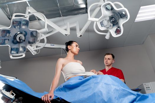 Surgeon with woman patient in operating room before breast augmentation for girl. Doctor wraps around the patient chest after breast augmentation.