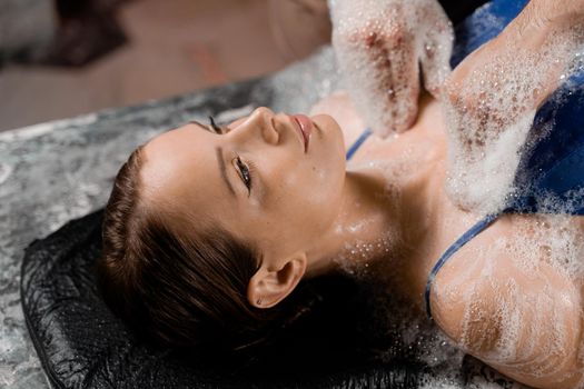 Close-up foam peeling massage for model in spa. Relaxation in Turkish hammam.