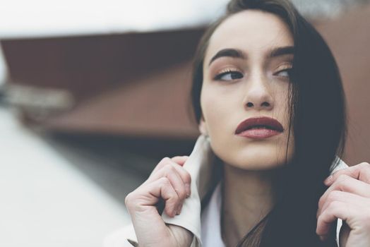 Outdoor portrait of a young beautiful fashionable lady wearing stylish coat . Model looking aside. Female fashion concept. City lifestyle. Close up. big plump lips