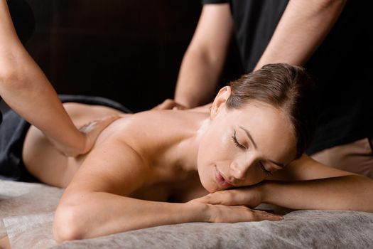 4 hands massage in spa. Two masseurs are making four hands relaxing massage with oil for girl. Relaxation. Manual therapy.