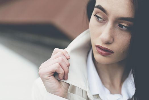 Outdoor portrait of a young beautiful fashionable lady wearing stylish coat . Model looking aside. Female fashion concept. City lifestyle. Close up. big plump lips