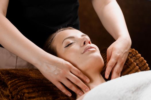 Facial massage close-up in spa center. Girl with perfect skin relaxing in massage room