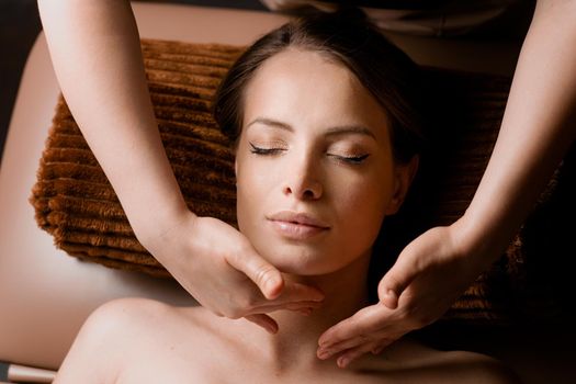 Neck and face massage in the spa. Masseur is making facial beauty treatments for an attractive female model. Relaxation