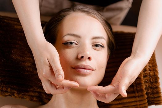 Masseur is making facial massage in spa for model with perfect skin. Beauty procedure