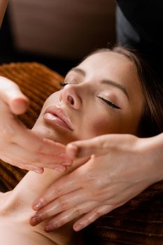 Neck and face massage in the spa. Masseur is making facial beauty treatments for an attractive female model. Relaxation