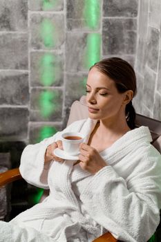 Inhalation therapy in salt room in spa. Young woman with cup of tea relaxing