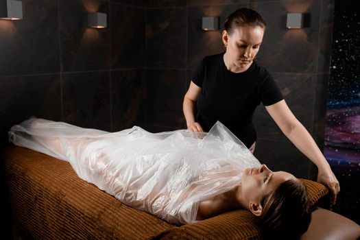 Woman wrapped in a polyethylene wrap. Chocolate Spa therapy.