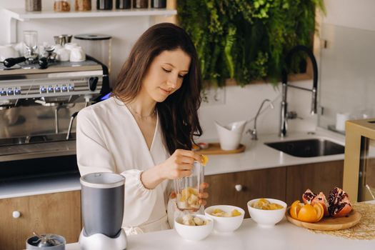 a girl makes a detox cocktail of fruit in the kitchen . Diet for weight loss.