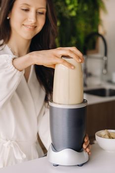 a girl makes a cocktail in a fruit blender in the kitchen. Diet for weight loss.