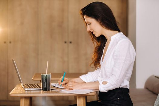 The girl is sitting at a desk in the office and working.