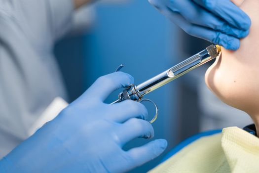 Dentist injects anesthesia syringe of the diseased teeth for the patient. Caries treatment