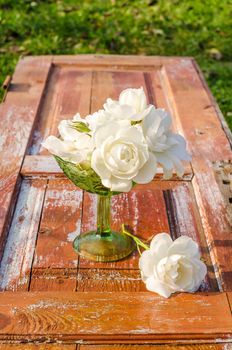 Beautiful bouquet of roses with drops in green glass vase on old wooden table. After the rain. Rustic style.