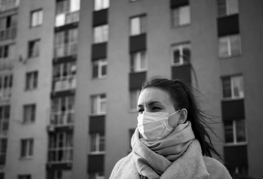 Shot of a girl in wearing face mask for protection, on the street. Against the background of a residential building with windows. lockdown Covid-19 pandemic.