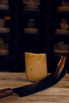 Parmesan hard aged cheese with dutch cheese knife on dark background. Snack tasty piece of cheese for appetizer
