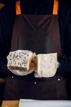 Blue cheese and gouda with italian herbs in hands. Holding dorblu, gorgonzola, roquefort. French gourmet cuisine.