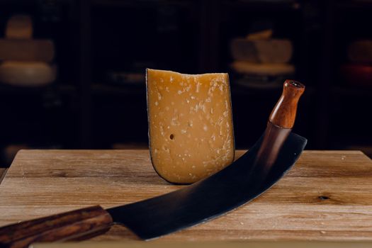 Parmesan hard aged cheese with dutch cheese knife on dark background. Snack tasty piece of cheese for appetizer