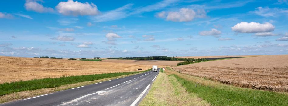 camper van on empty country road in the north of france near reims in champagne ardennes under blue sky in summer