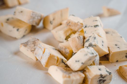 Mix of cheeses on plate. Slicing blue cheese dorblu, gorgonzola, roquefort. French gourmet traditional cuisine.