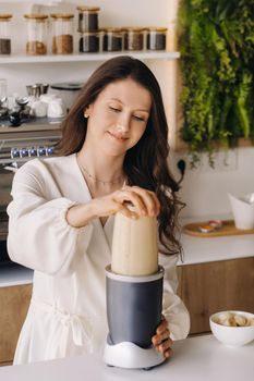 a girl makes a cocktail in a fruit blender in the kitchen. Diet for weight loss.