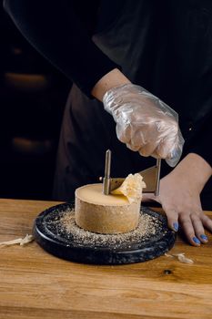 Shaving tete de moine cheese using girolle knife. Monks head. Variety of Swiss semi-hard cheese made from cows milk.