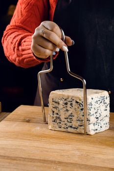 String for slicing blue cheese. Mix of cheeses on plate. Slicing dorblu, gorgonzola, roquefort. French gourmet cuisine