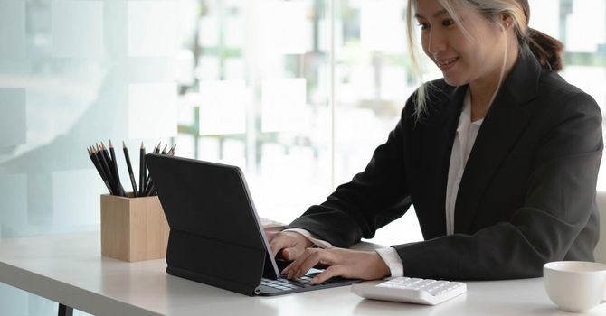 Young Asian businesswoman is happy to work at the modern office using a tablet..