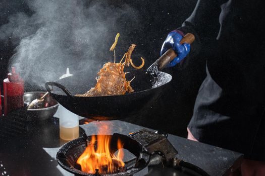 Flying flambe noodles for wok box with meat, soy sauce fried in a wok pan, street food.