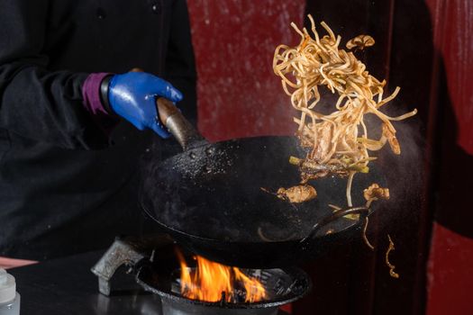 Flying noodles for wok box with meat, soy sauce fried in a wok pan, street food.